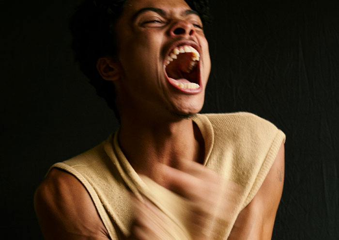 Angry man shouting with intensity against a black background, illustrating behaviors that might make women feel unsafe.