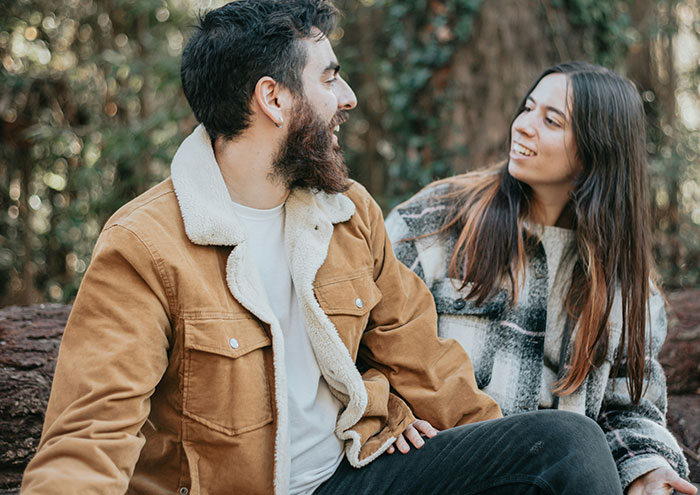 Man and woman sitting outdoors in casual clothing, highlighting behaviors from men that might make women feel unsafe.