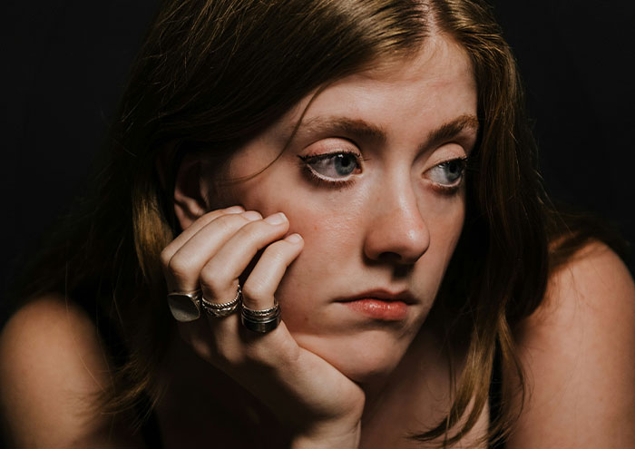 Young woman looking worried and reflective, illustrating behaviors from men that might make women feel unsafe.