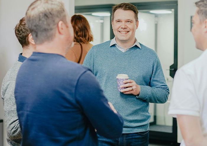 A group of men casually talking indoors, illustrating behaviors from men that might make women feel unsafe.