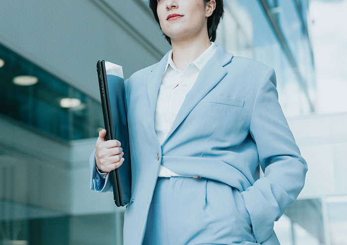 Confident woman in light blue suit holding a folder, representing behaviors from men that might make women feel unsafe.