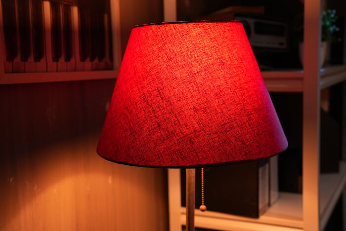 Red lampshade glowing softly in a dimly lit room, creating a creepy and eerie atmosphere often seen in unsettling Reddit posts.