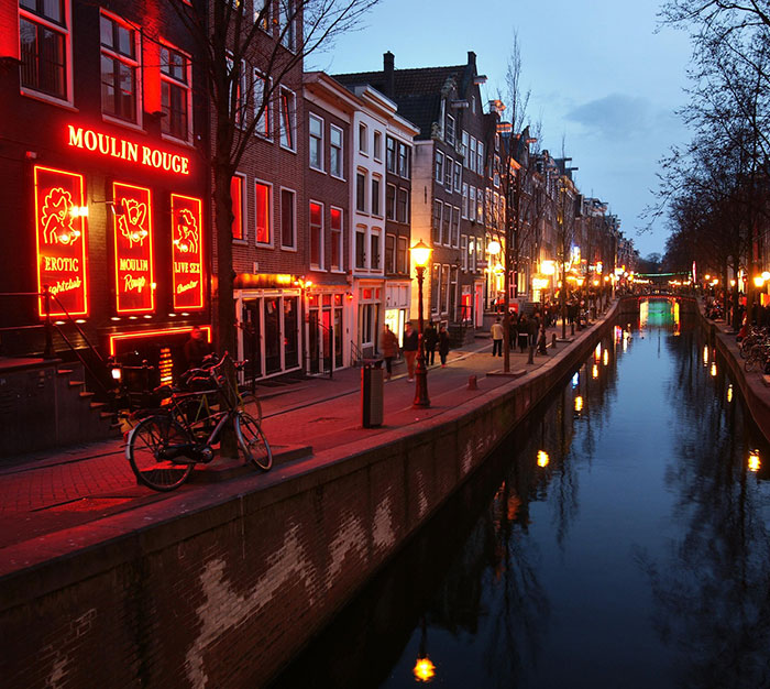 Canal street at night with brothel signage lit up, depicting brothel manager revealing ways men get caught by partners. - 2