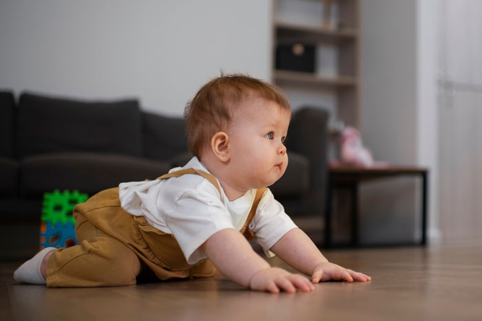 Baby crawling indoors on wooden floor, illustrating a medical condition related to shoes in a friend's house scenario.