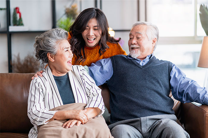 Elderly parents with smiling daughter on couch, expecting support after losing savings on risky business schemes. Elderly parents with smiling daughter on couch, expecting support after losing savings on risky business schemes.
