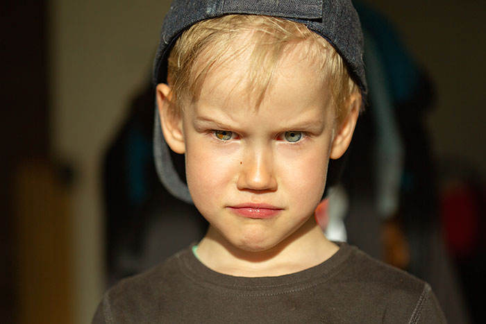 Young boy with intense stare wearing a backwards cap, illustrating the concept of growing up with a psychopath.