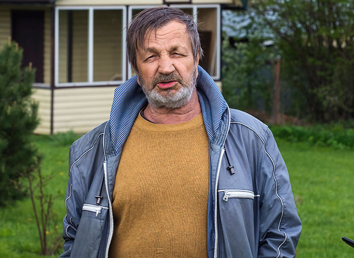 Middle-aged man with weathered face wearing a jacket and sweater, symbolizing growing up with a psychopath experience.
