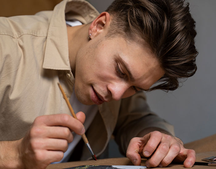Young man focused on painting details, illustrating a creative expression linked to experiences with a psychopath.