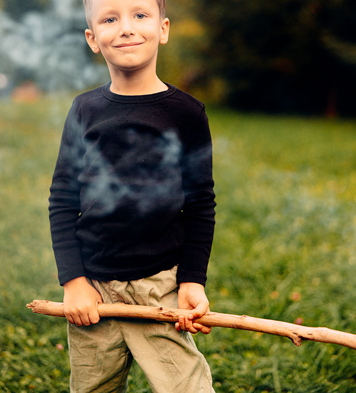 Young boy holding a large stick outdoors, symbolizing fears and experiences of those who grew up with a psychopath.