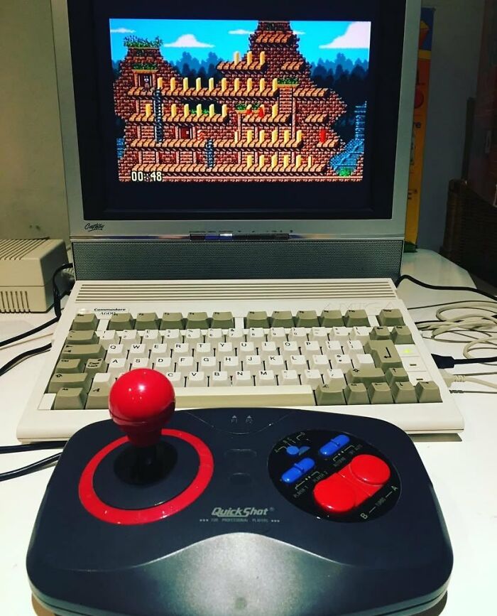 Vintage computer with retro gaming joystick and pixel art game on screen, evoking nostalgia for classic gaming.