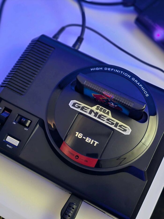 Retro gaming console Sega Genesis 16-bit with cartridge inserted, evoking nostalgia for ’80s and ’90s gamers.