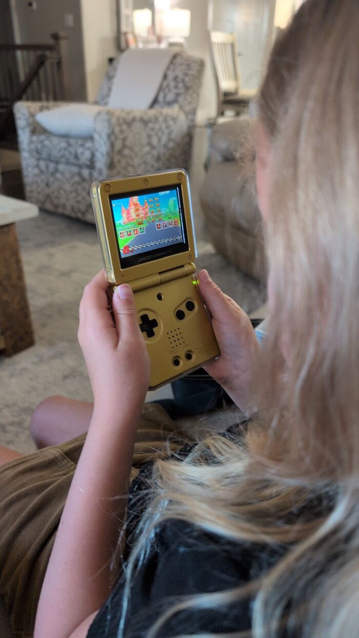 Child playing retro gaming on a vintage handheld console, enjoying nostalgia from 80s, 90s, and 00s video games.