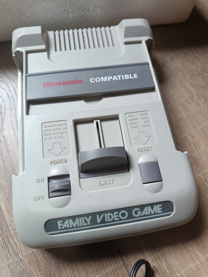Retro gaming console labeled Family Video Game compatible with Nintendo, showing power, eject, and reset buttons on wood surface.