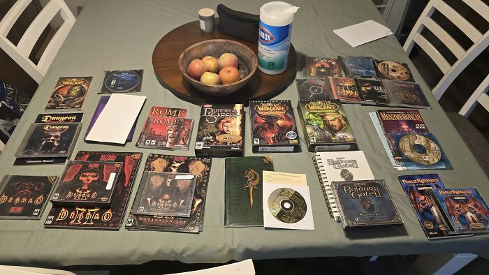 Collection of retro gaming PC game boxes and discs from the ’80s, ’90s, and ’00s displayed on a dining table.