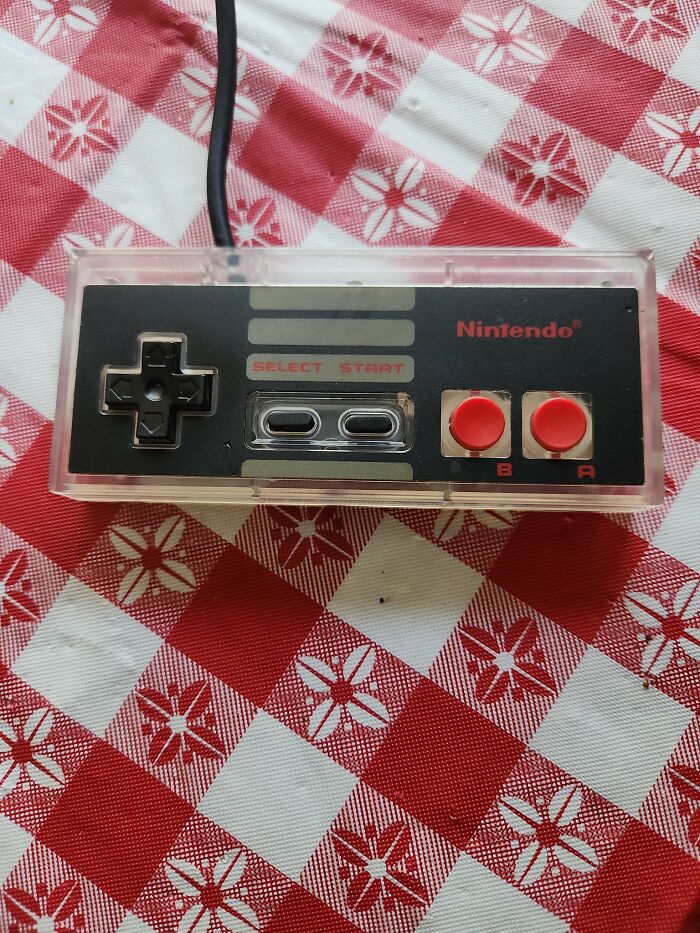 Retro gaming nostalgia with a classic Nintendo controller featuring red buttons on a red and white checkered tablecloth.