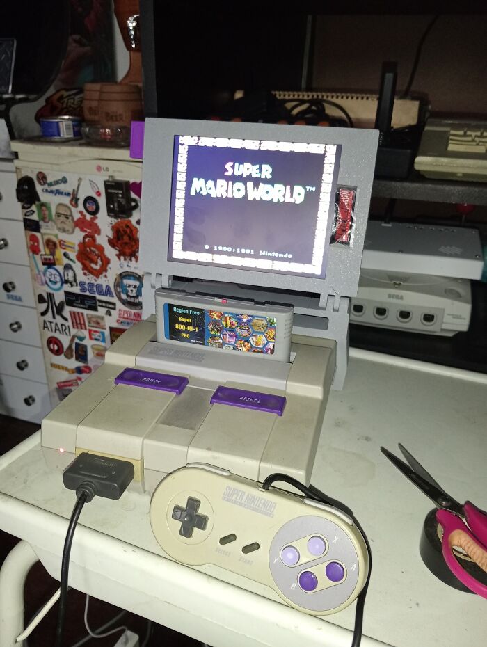 Retro gaming setup featuring Super Nintendo with Super Mario World on screen and classic controller on a white table.