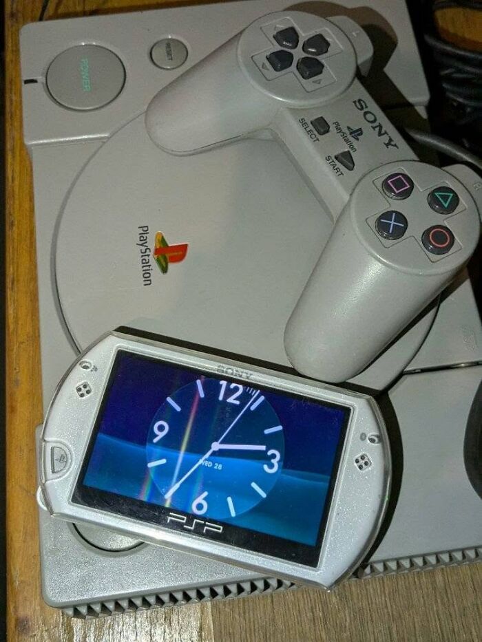 Sony PlayStation console and controller with a PSP handheld device displaying a clock, highlighting retro gaming nostalgia.