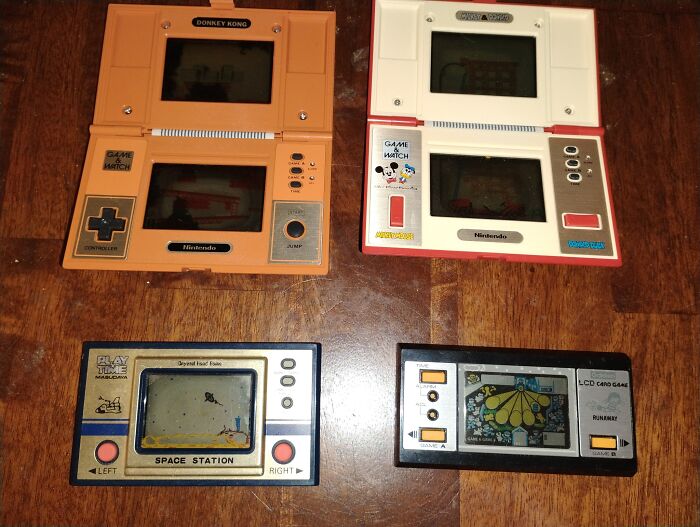 Four vintage handheld electronic games on a wooden surface showcasing retro gaming and nostalgia from the 80s, 90s, and 00s.