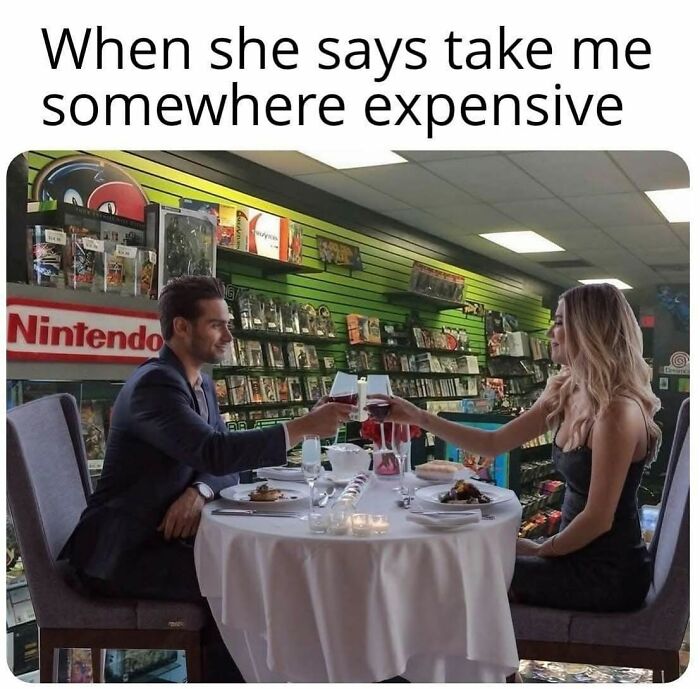 Couple toasting with wine in a retro gaming store, surrounded by nostalgic video game memorabilia and consoles.