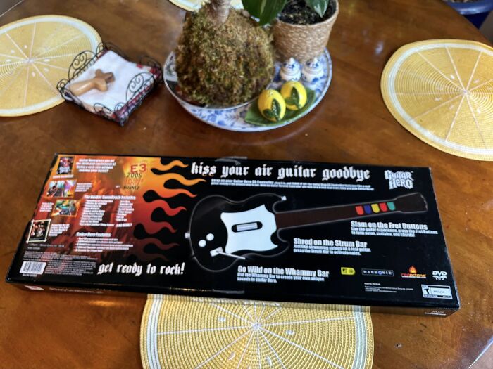 Air Guitar Hero game controller box on a wooden table, evoking retro gaming and nostalgia vibes.