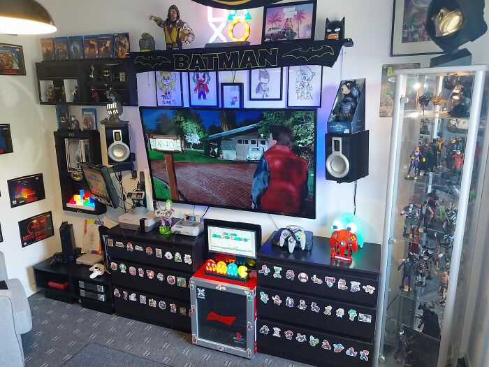 Gaming room with retro gaming consoles, Batman memorabilia, and nostalgia-themed collectibles from the 80s, 90s, and 00s.