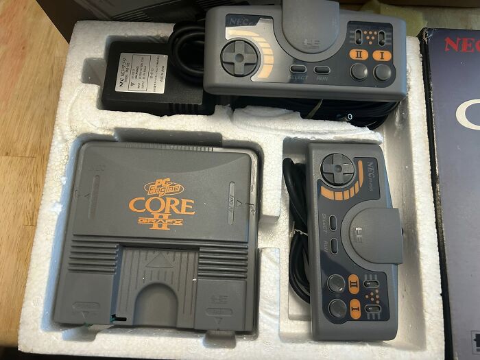 Retro gaming console and controllers in original packaging, showcasing 90s nostalgia and classic gaming gear.