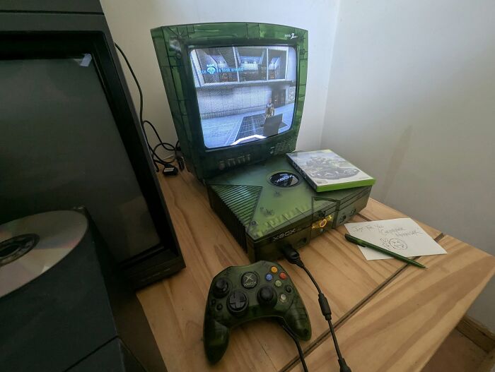 Retro gaming setup with original Xbox and CRT TV displaying gameplay on a wooden desk, evoking 90s nostalgia.
