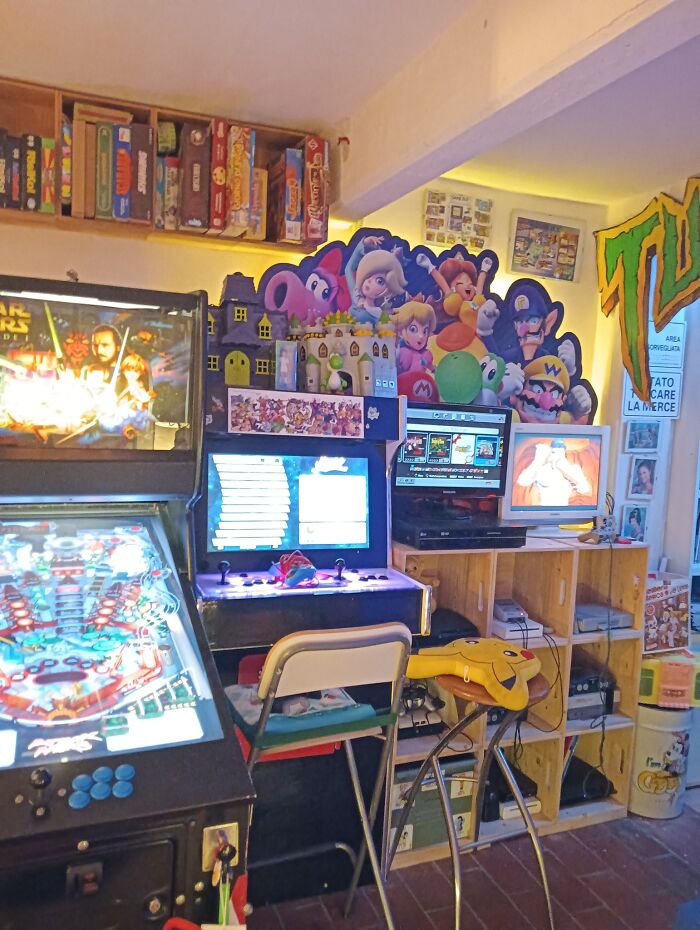 Retro gaming setup with arcade machines, vintage consoles, and nostalgic decorations from the 80s, 90s, and 00s era.