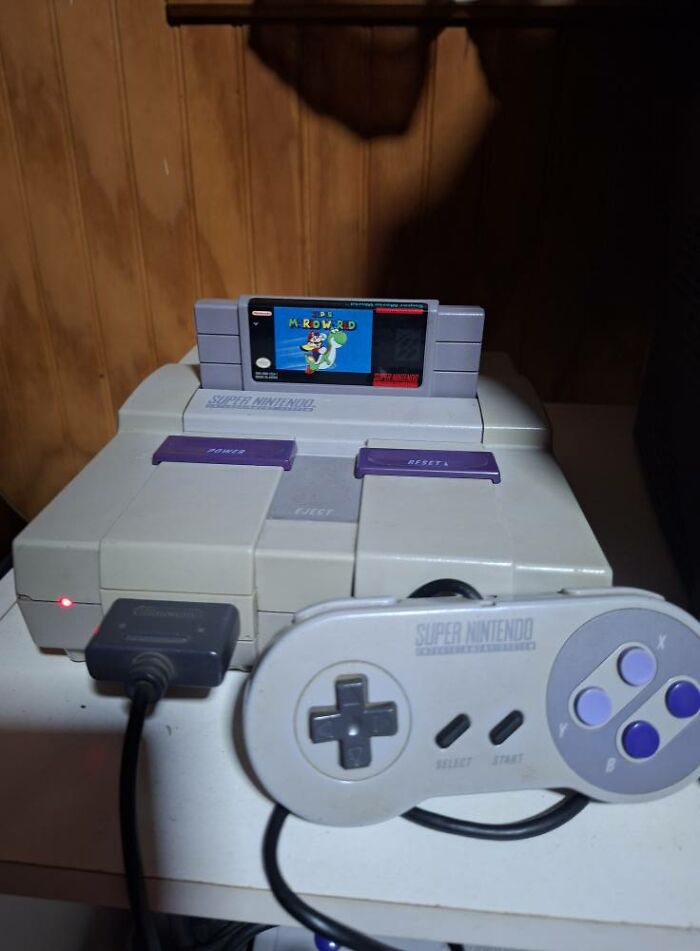 Super Nintendo console with controller and Super Mario World game cartridge, classic retro gaming nostalgia from the ’90s.