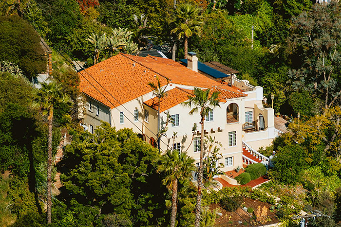 Large luxury home with red tile roof surrounded by trees, illustrating absurd things rich people spend money on.