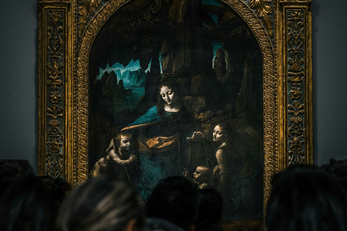 Visitors gathered in front of an ornate framed painting, illustrating absurd things rich people spend money on in art.