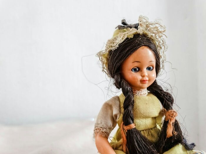Vintage doll with braided hair and lace bonnet, illustrating unexpected items on wedding registries including a coffin.