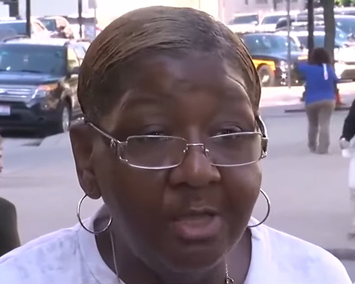 Woman wearing glasses speaking outdoors in a busy city street amid Cincinnati brawl victim&rsquo;s swollen face outrage.