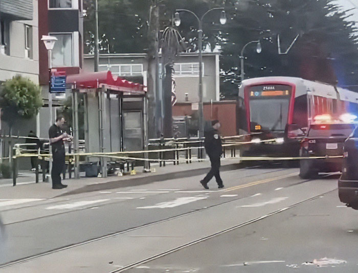 Police securing a transit area with tape near a stopped tram after a good Samaritan protects helpless mom and children.