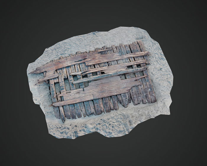 Aerial view of the Sanday ship wreck wooden planks partially buried in sand on a dark background.