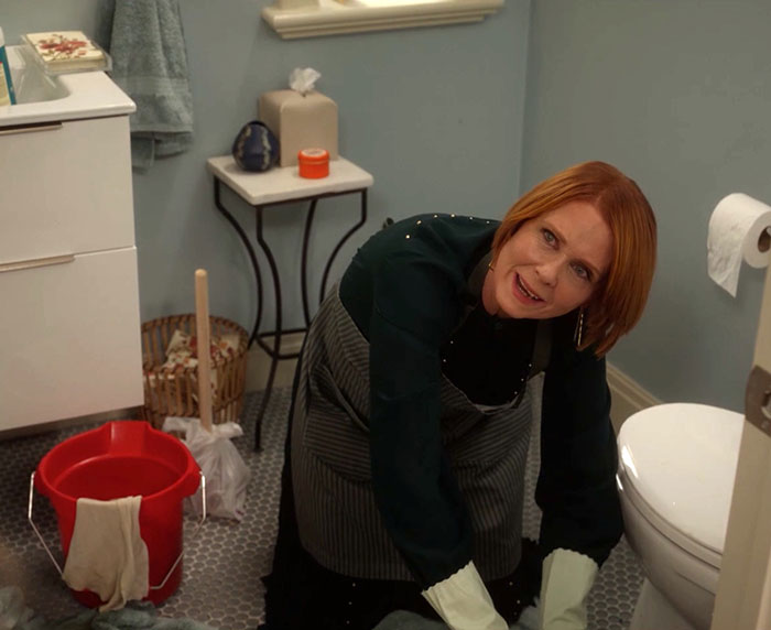 Woman cleaning bathroom floor wearing gloves and apron, relating to Sarah Jessica Parker clapping back at haters. Woman cleaning bathroom floor wearing gloves and apron, relating to Sarah Jessica Parker clapping back at haters.
