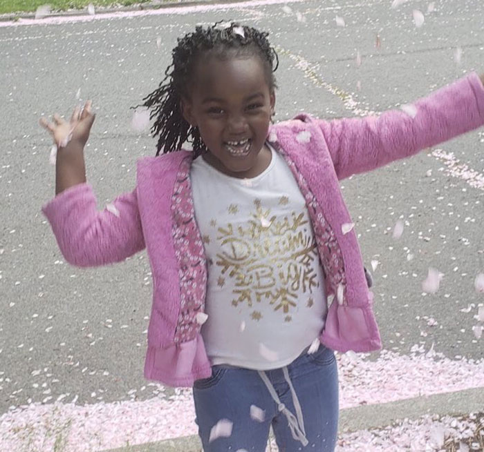 Young girl outside joyfully playing in falling petals, related to hospital fires 15 nurses after 12-year-old patient crisis.
