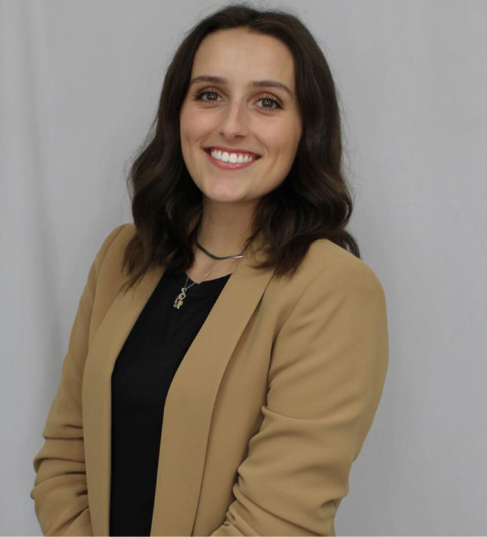 Young woman smiling, wearing a tan blazer and black top, representing emotions after messy painful divorce and ex’s passing at 48. Young woman smiling, wearing a tan blazer and black top, representing emotions after messy painful divorce and ex’s passing at 48.