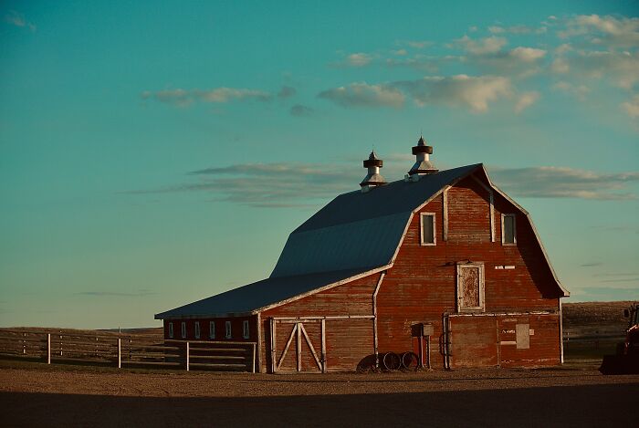 Old red barn at sunset with a clear sky, evoking a creepy atmosphere related to things people saw on Reddit.