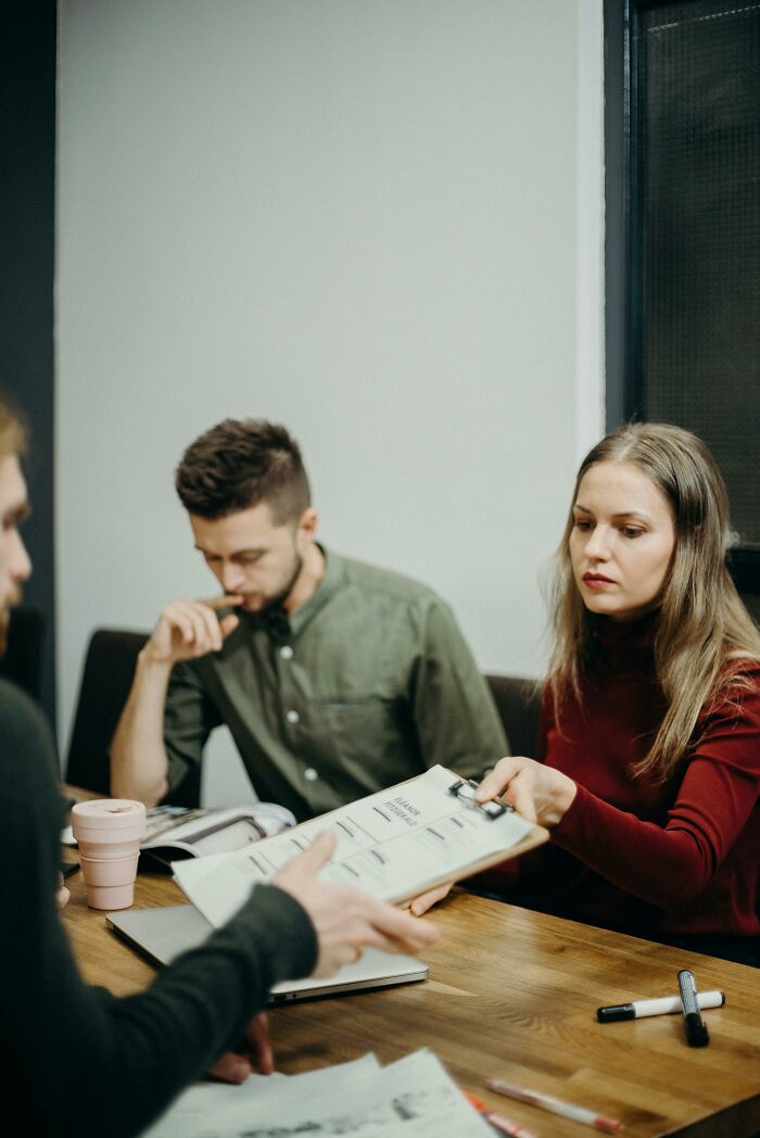 Three millennials in a meeting, reviewing documents and discussing potential scams targeting their generation.