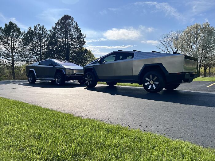 Two futuristic silver electric vehicles parked on a driveway under a blue sky, symbolizing the alpha vibe and overcompensation traits. - 11