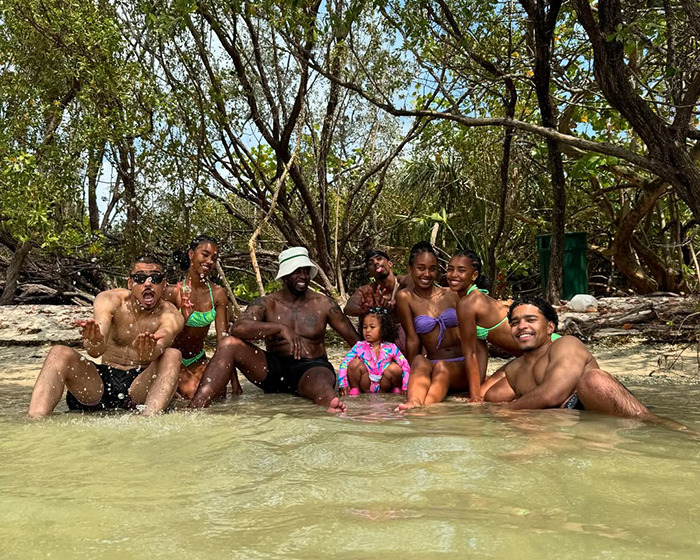 Sean Diddy Combs and family relaxing in the water at a tropical location surrounded by trees and greenery.