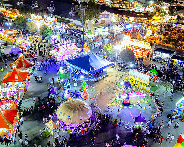 Brightly lit amusement park at night with crowds enjoying rides, linked to Sean Diddy's twin daughters' rollercoaster incident.