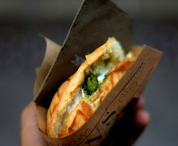 Close-up of a toasted sandwich with broccoli filling held in hand, highlighting toxic broccoli sandwich concerns.
