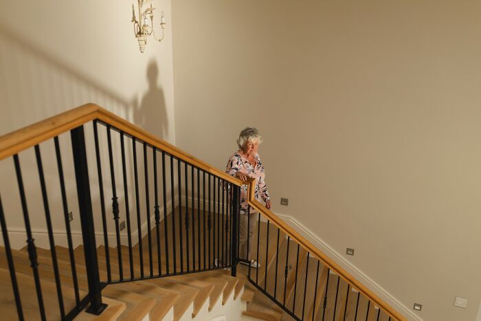 Elderly woman standing on stairs casting a shadow, illustrating glitches in the matrix people experienced concept.