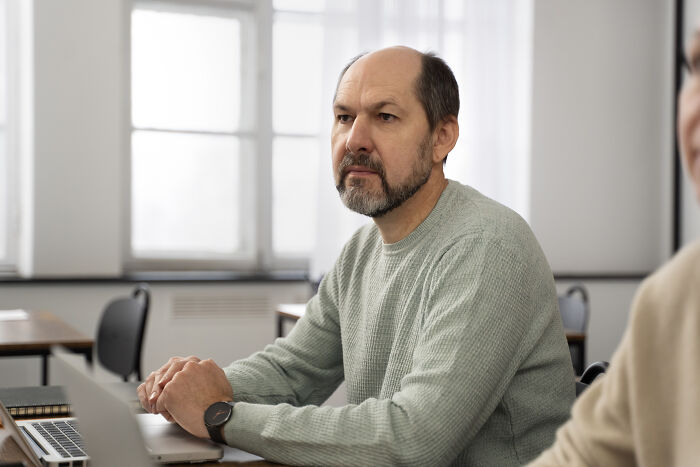 Middle-aged man in a grey sweater sitting in an office, reflecting on challenges hiring managers face with difficult people.