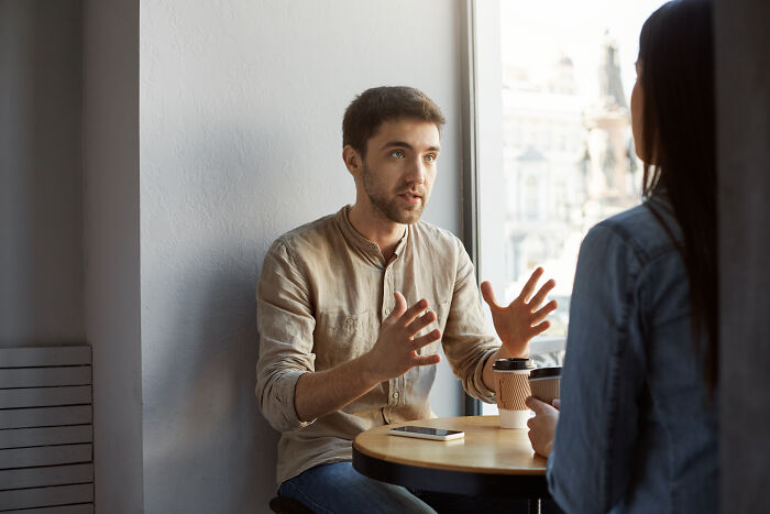 Two people having a conversation at a cafe table, illustrating words that don’t exist in English but used in other languages.