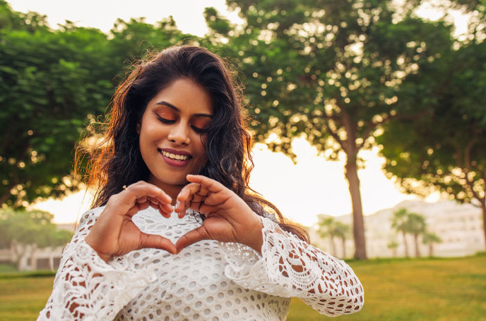 Young woman outdoors making a heart shape with hands, reflecting inspiration and positivity with short quotes theme.