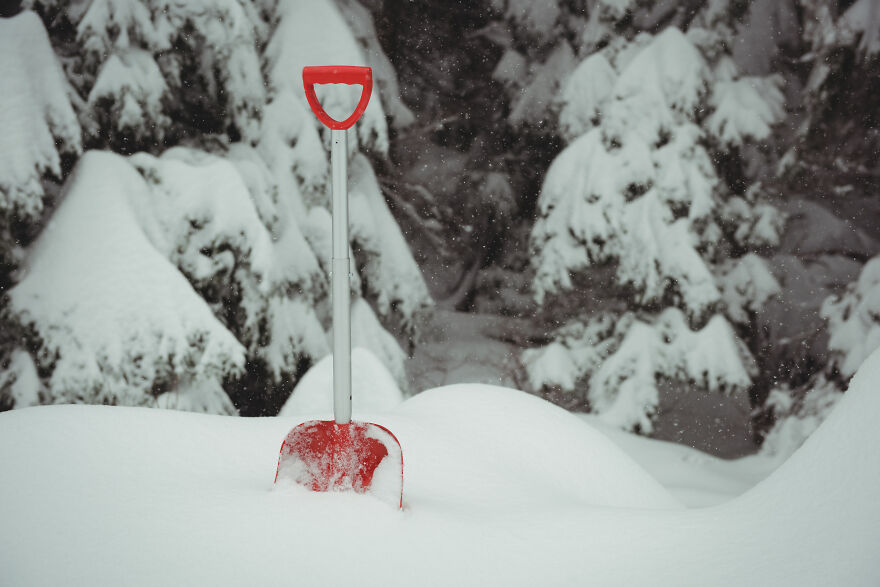 Red snow shovel stuck in deep snow with snow-covered trees in background illustrating claustrophobia feelings. Red snow shovel stuck in deep snow with snow-covered trees in background illustrating claustrophobia feelings.