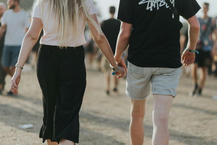 Couple holding hands outdoors with focus on height difference, illustrating dating and short king height preferences.